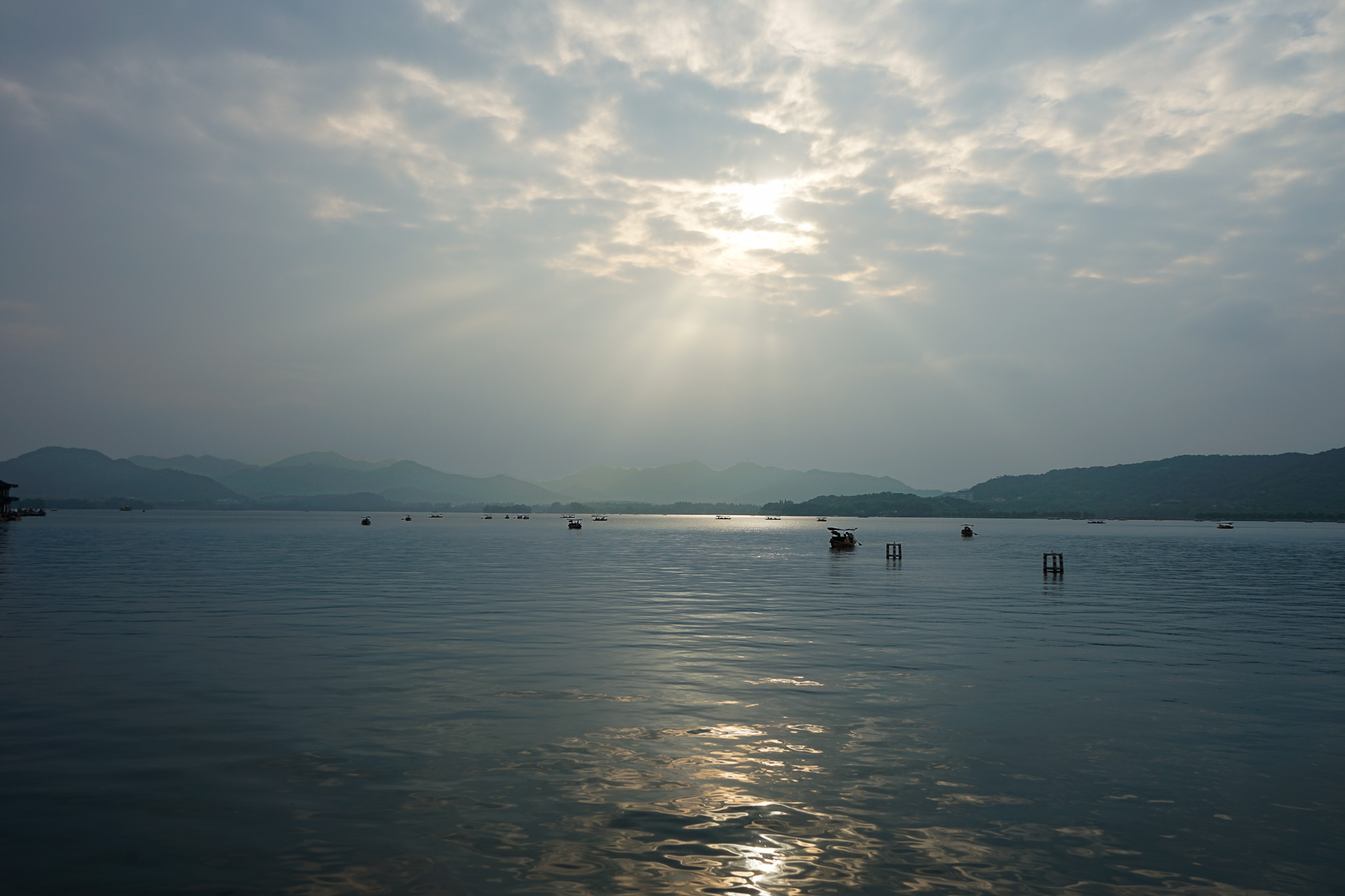 云隙间的阳光洒向湖面，远山与小船静立