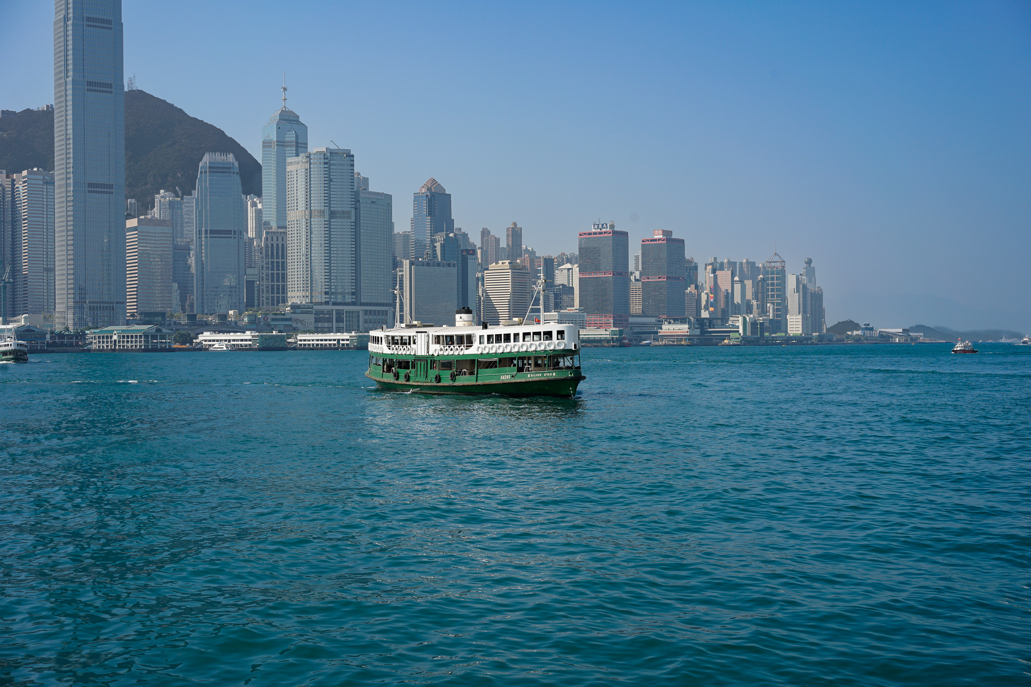 香港海港中的绿色渡轮与沿岸高楼